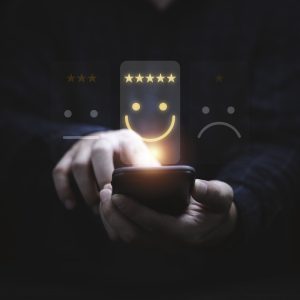 Businessman using smartphone for select smiley face icon for client evaluation and customer satisfaction after use product and service concept.