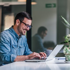 Delighted adult man, working on a company slogan, on his laptop.